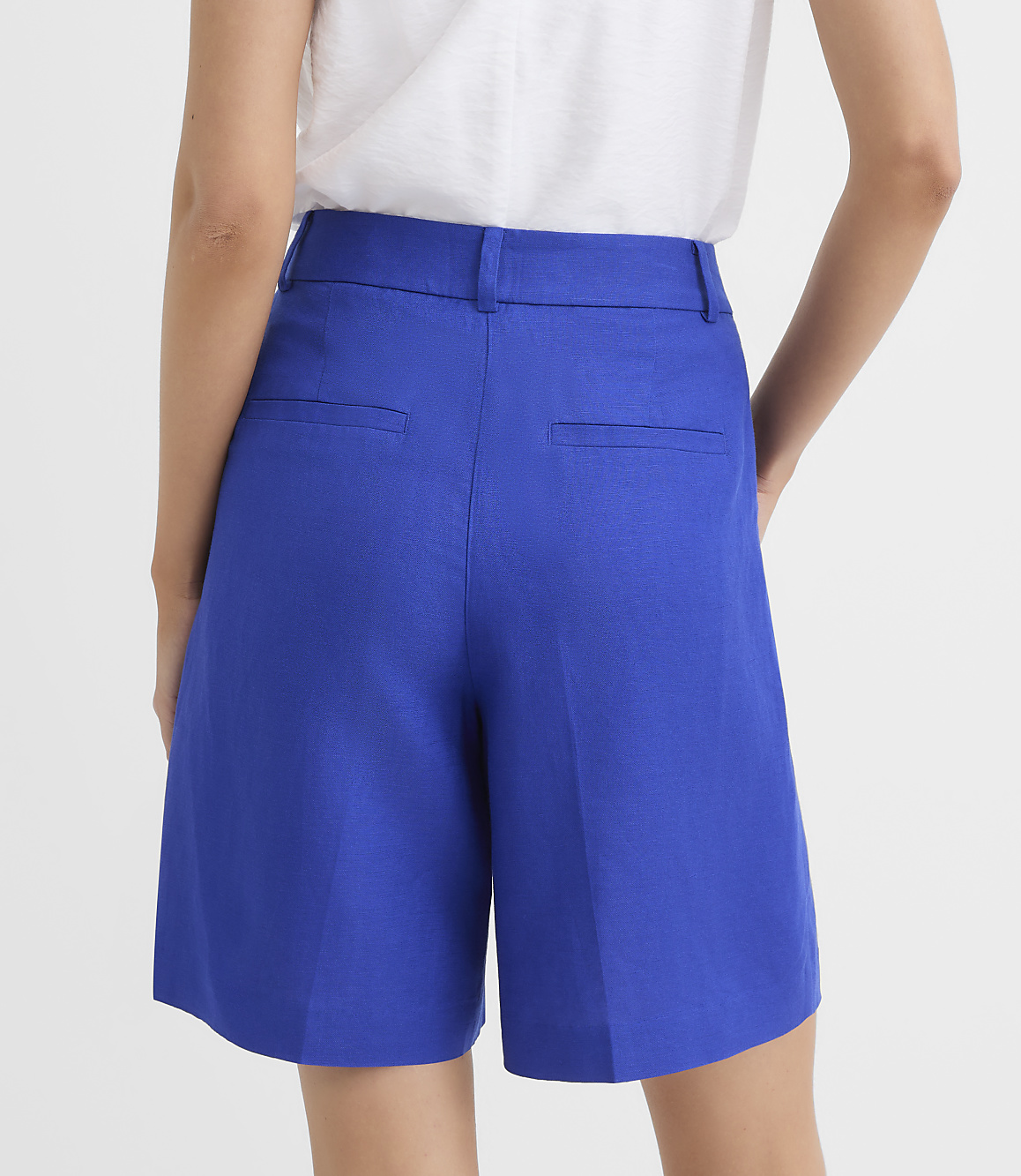 A person wearing bright blue shorts stands against a plain white background.