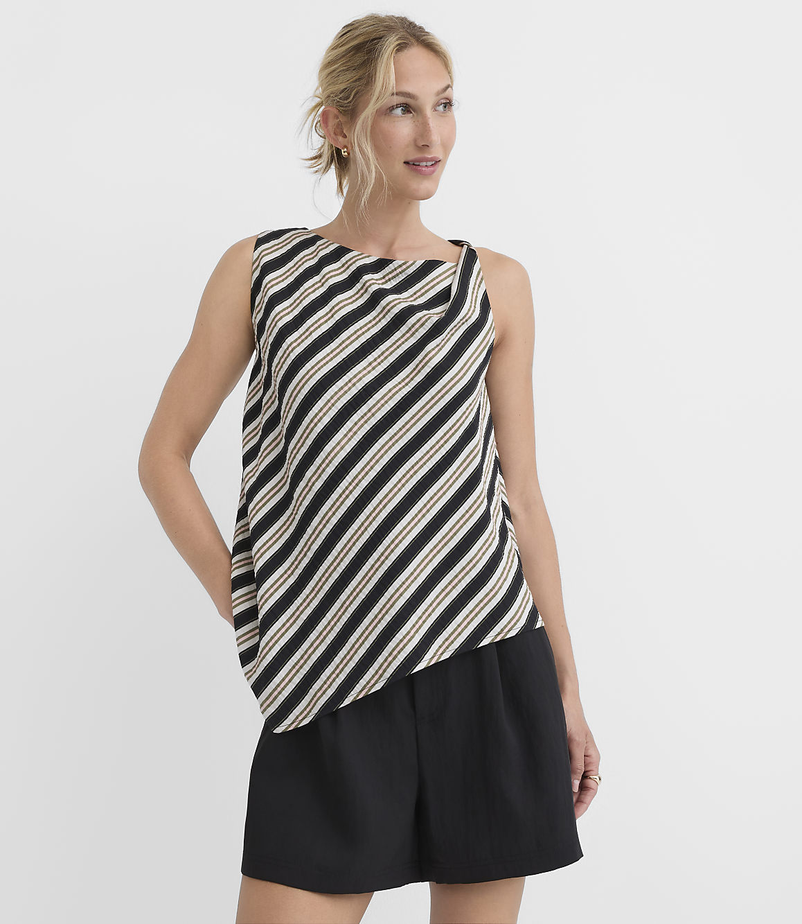 A woman in a striped top and black shorts stands against a plain white background.