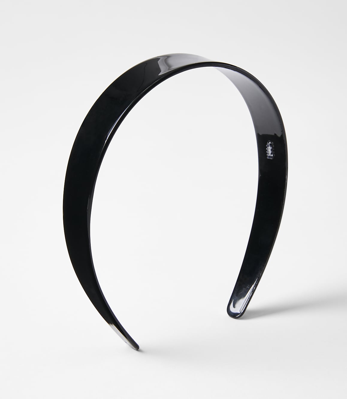 A glossy black headband rests on a plain white background.