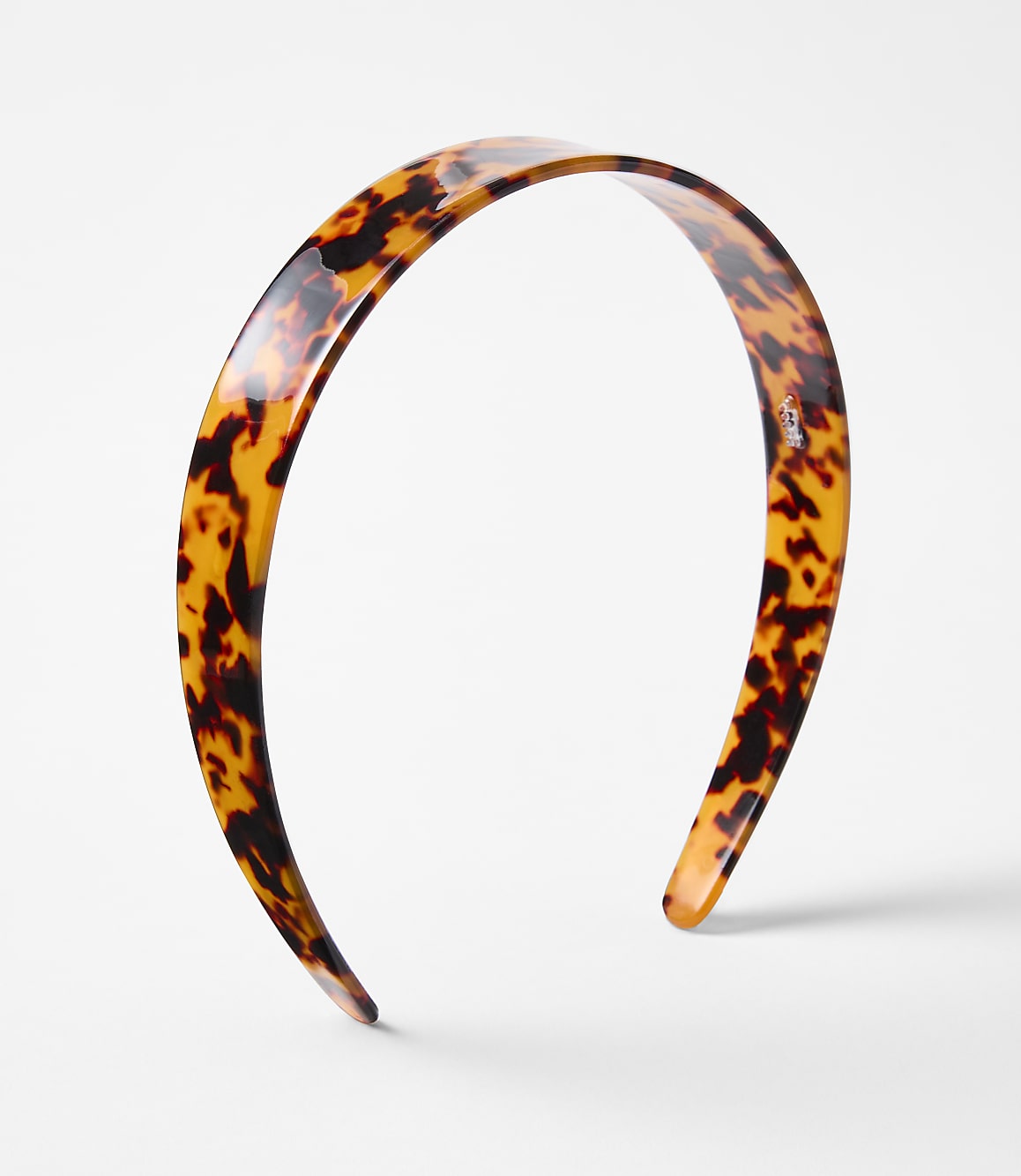 A tortoiseshell headband rests on a plain white background.