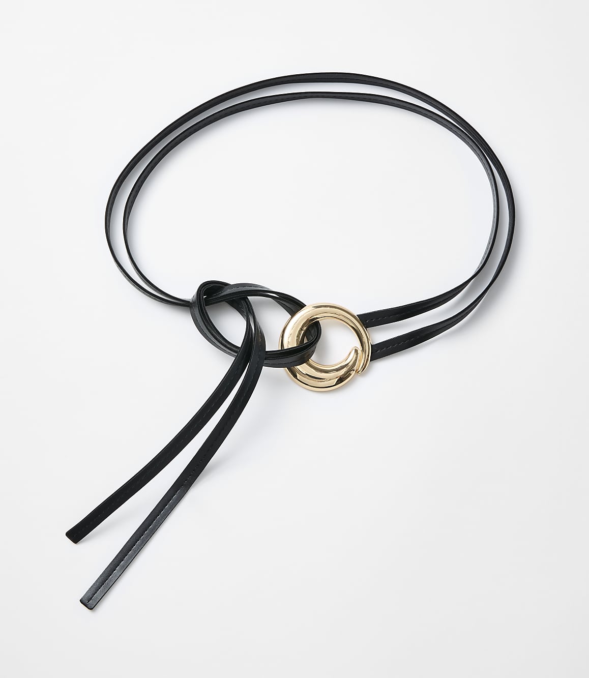 A black leather belt with a gold ring is laid out on a white background.