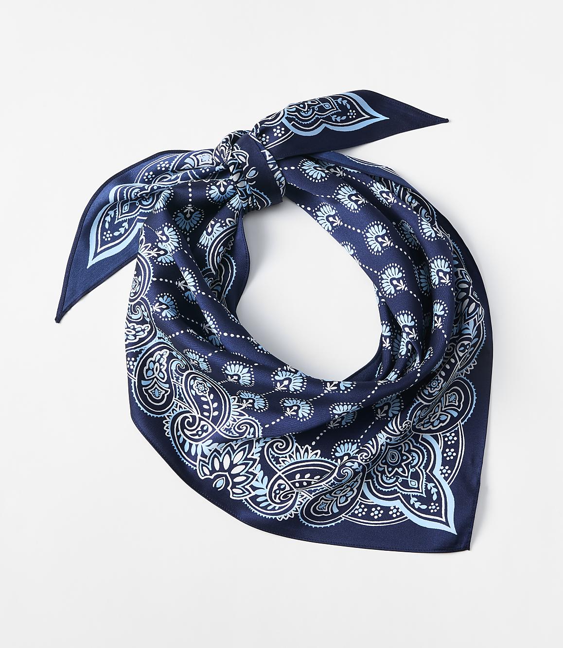 A dark blue bandana with a light blue paisley pattern is tied in a knot against a plain white background.