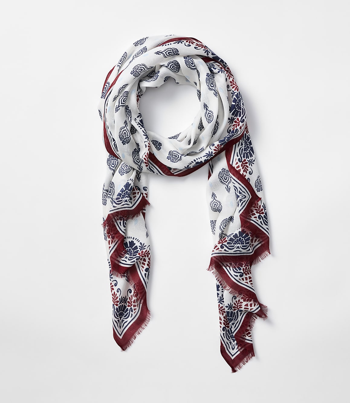 A white scarf with a red and blue paisley pattern is draped against a plain white background.