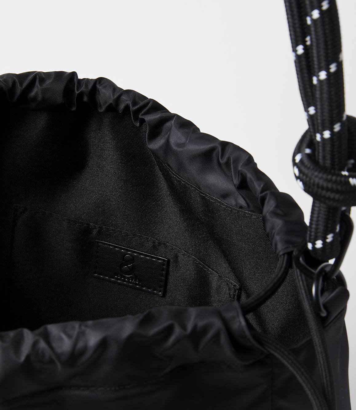 A black drawstring bag with a white-speckled rope strap is shown against a plain white background.