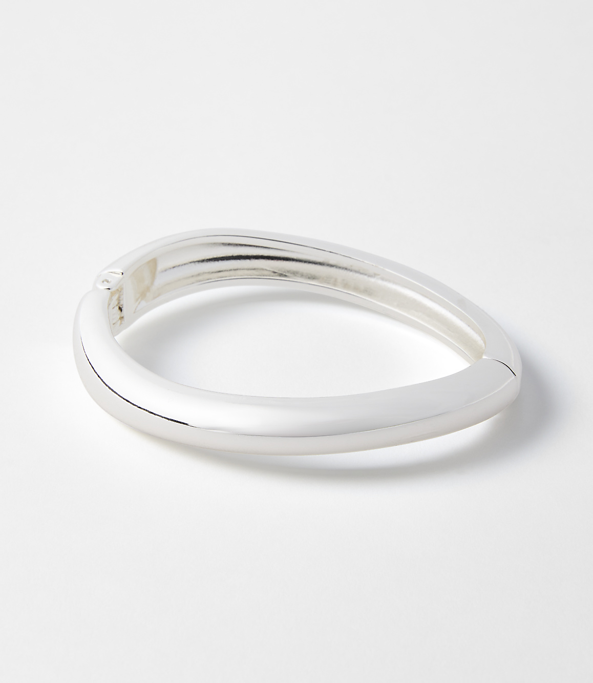 A sleek, silver bangle rests on a plain white background.