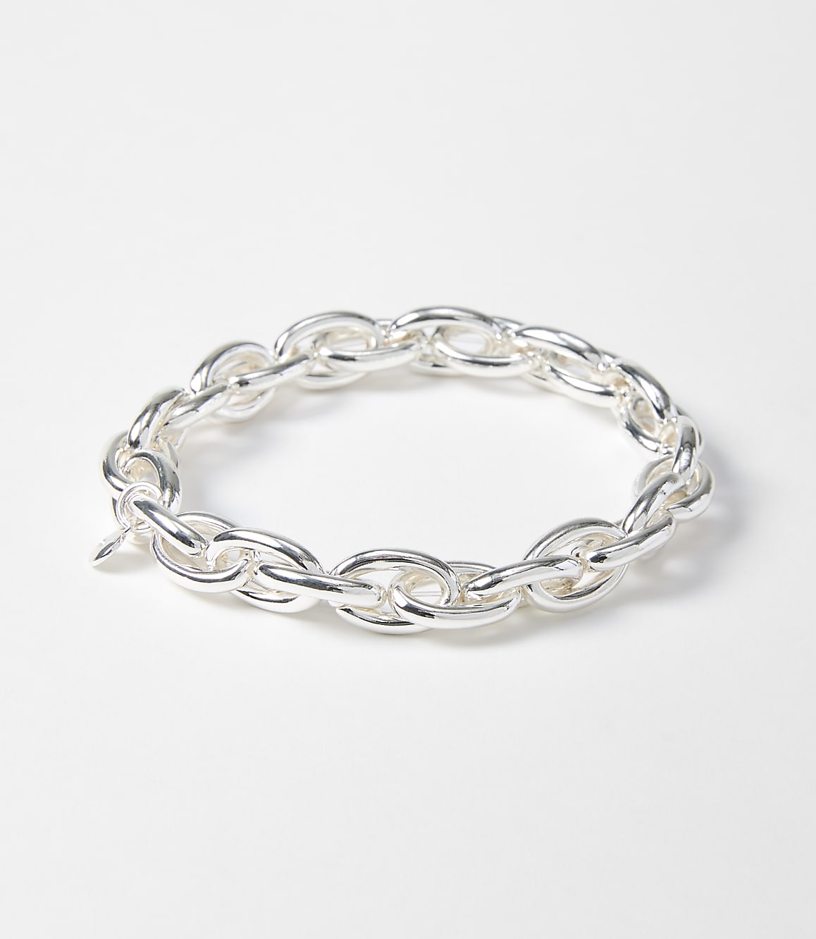A silver chain bracelet with oval links rests on a plain white background.