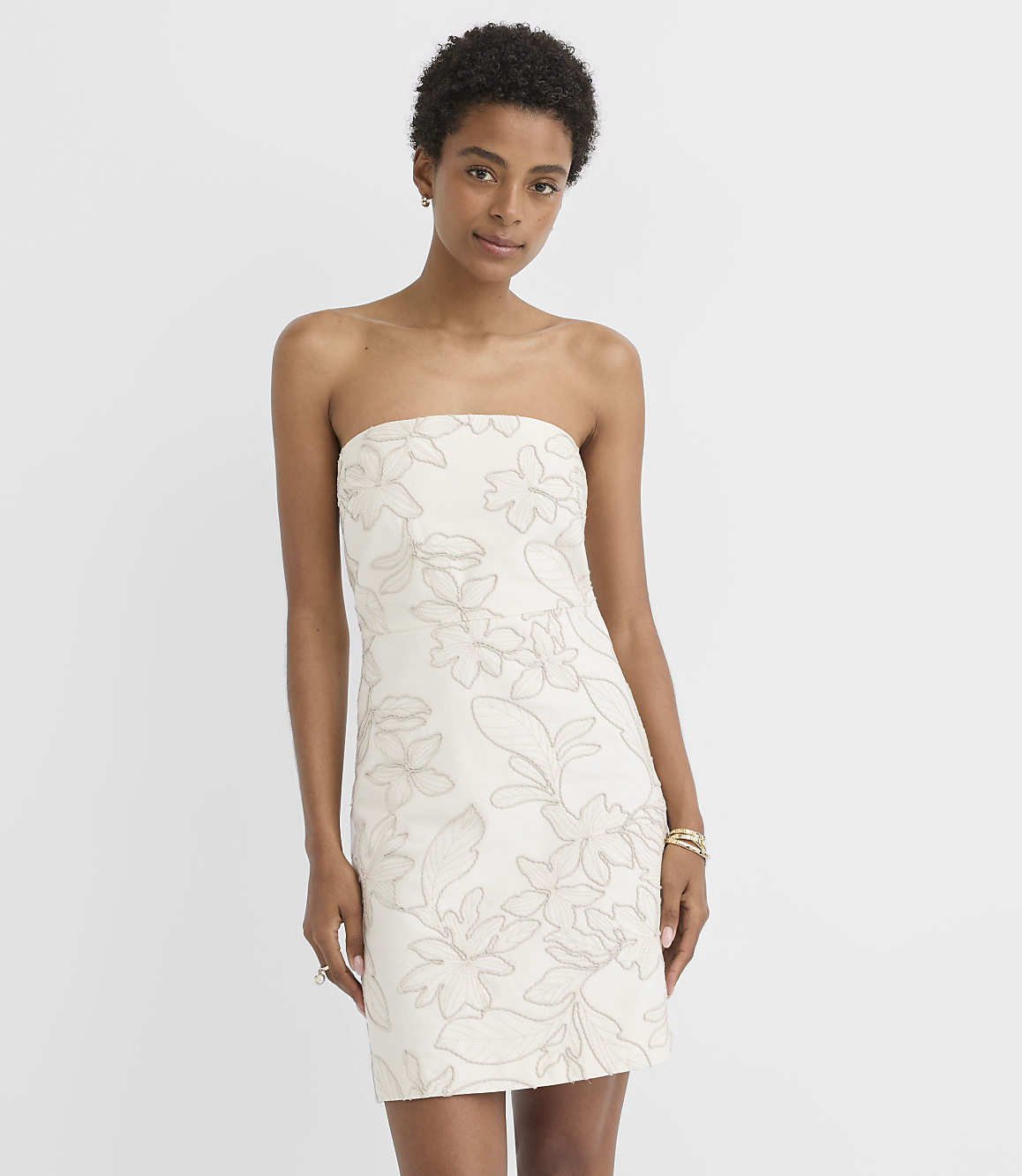 A woman in a strapless floral dress stands against a plain white background.