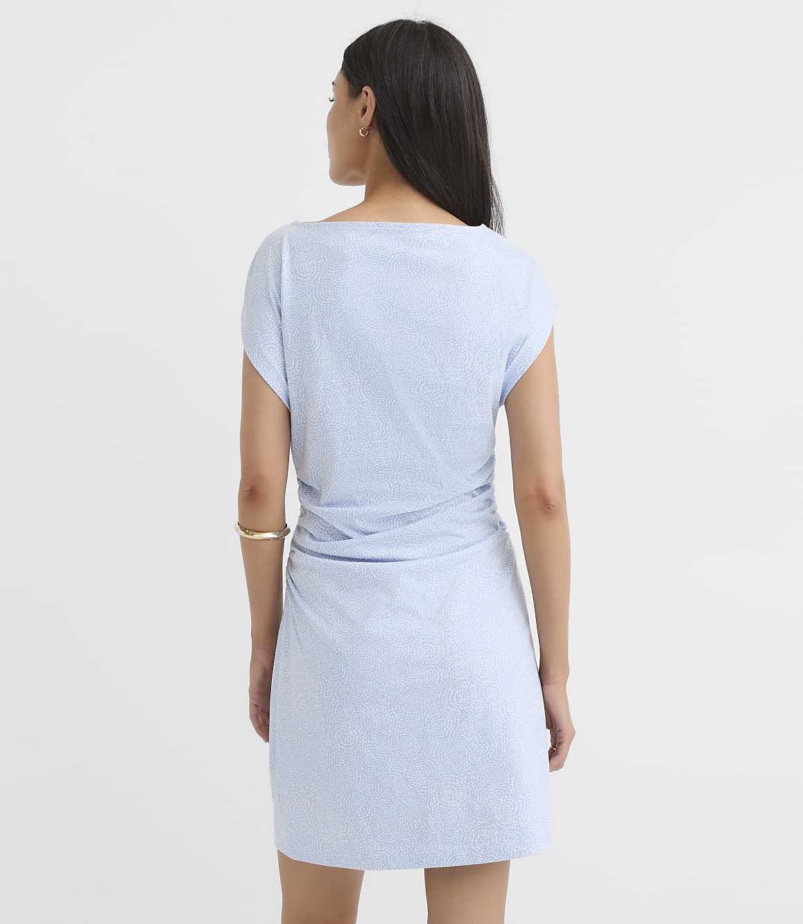 A woman in a light blue, textured dress stands against a plain white background.