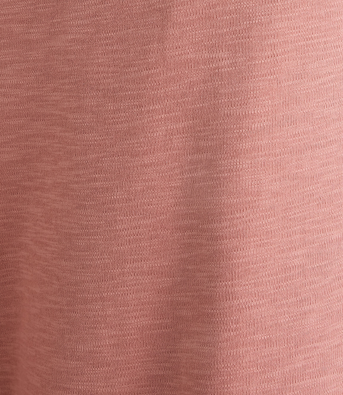 A close-up of a textured, dusty rose fabric fills the frame, with subtle variations in shade creating a soft, mottled background.