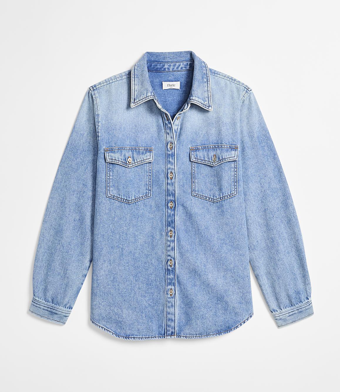 A light blue denim shirt with two chest pockets is laid flat against a plain white background.