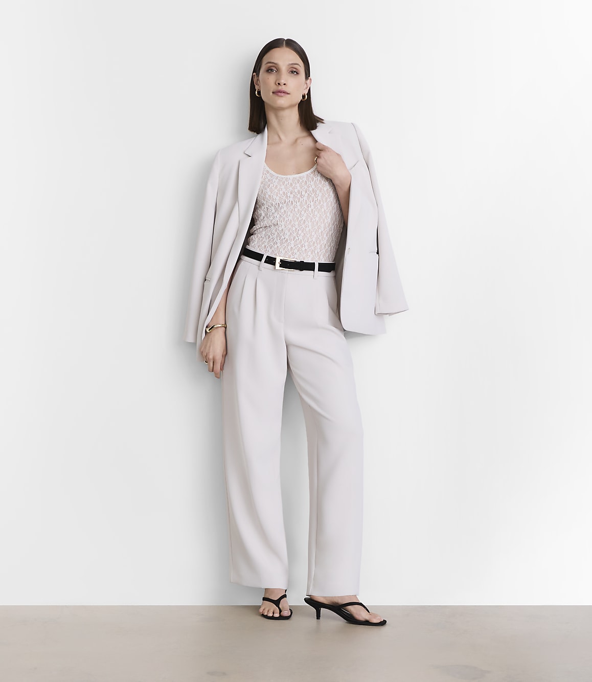 A woman in a light-colored suit stands against a plain white background.