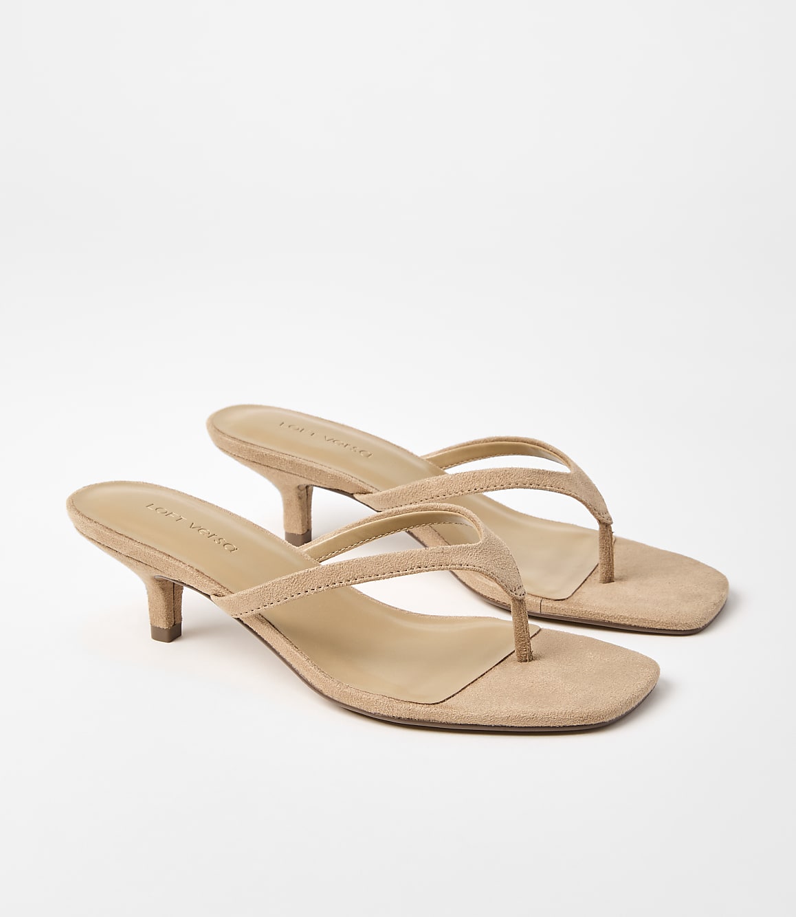 A pair of tan suede kitten heel thong sandals rests on a plain white background.
