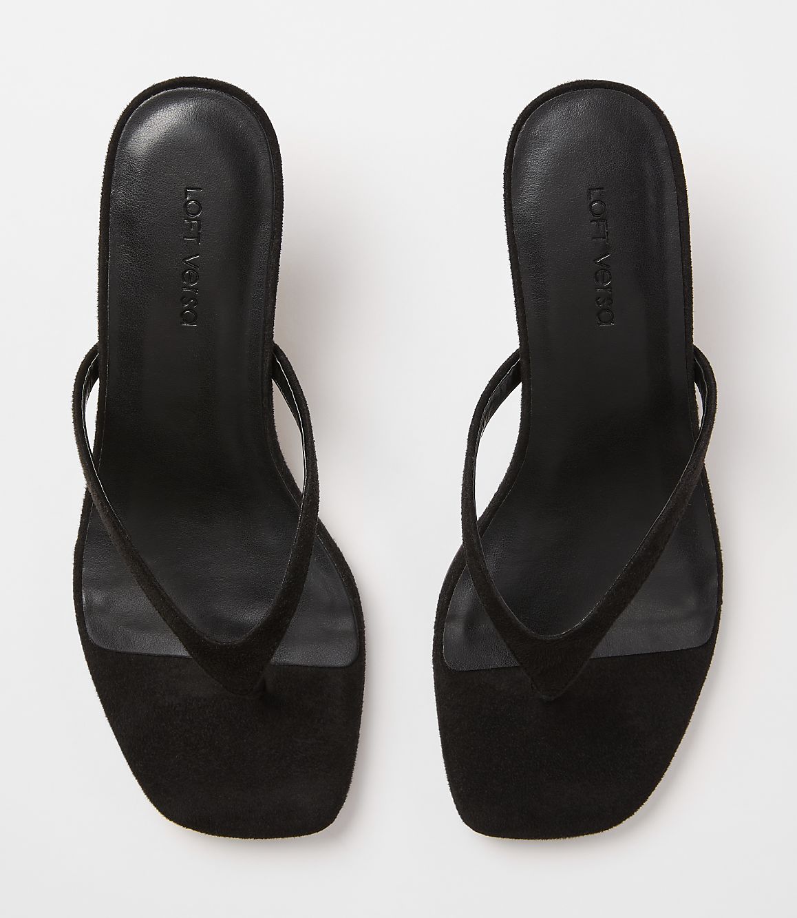 A pair of black suede thong sandals with square toes rests on a plain white background.