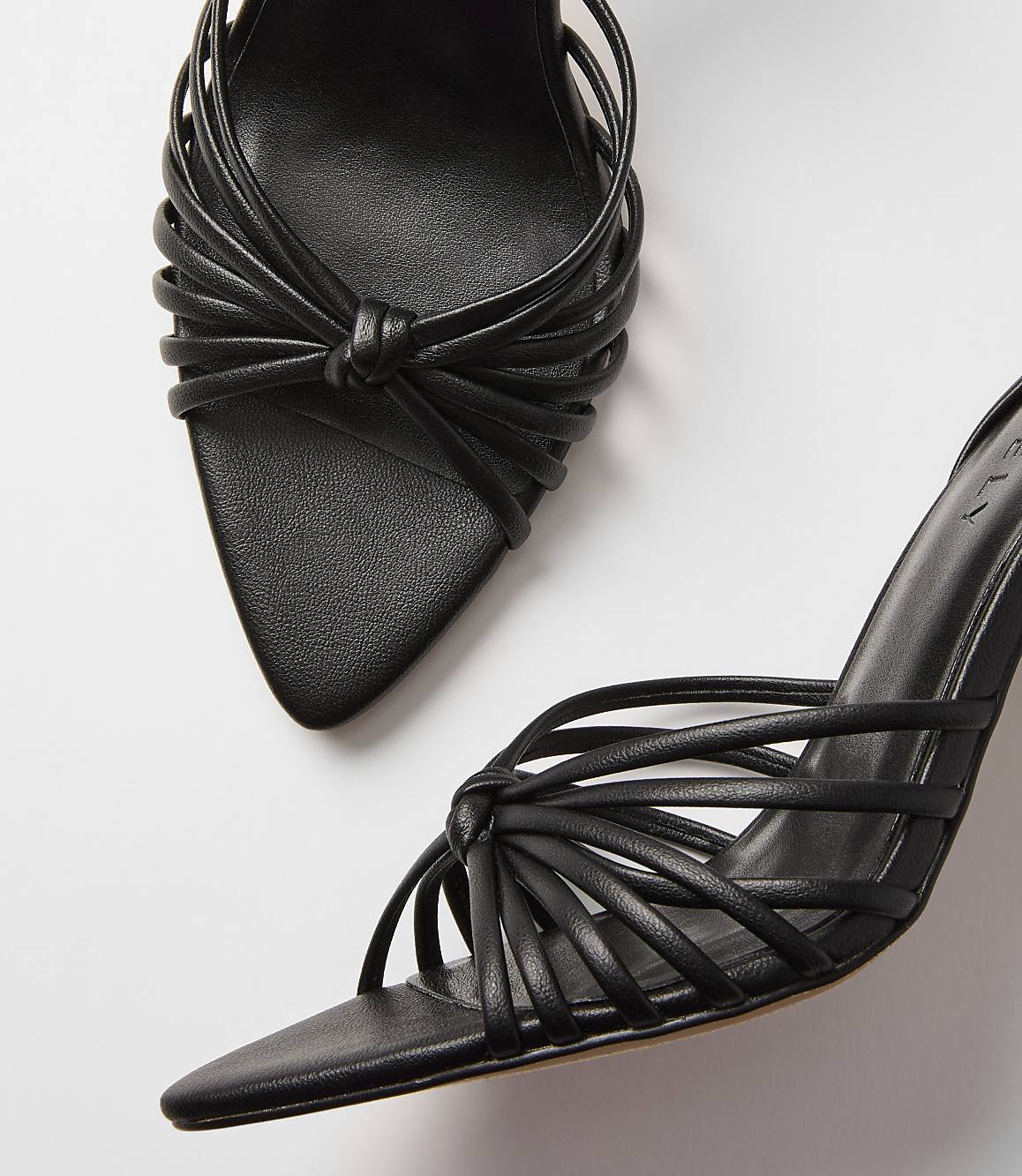 Black strappy heels with knotted details are arranged on a plain white background.