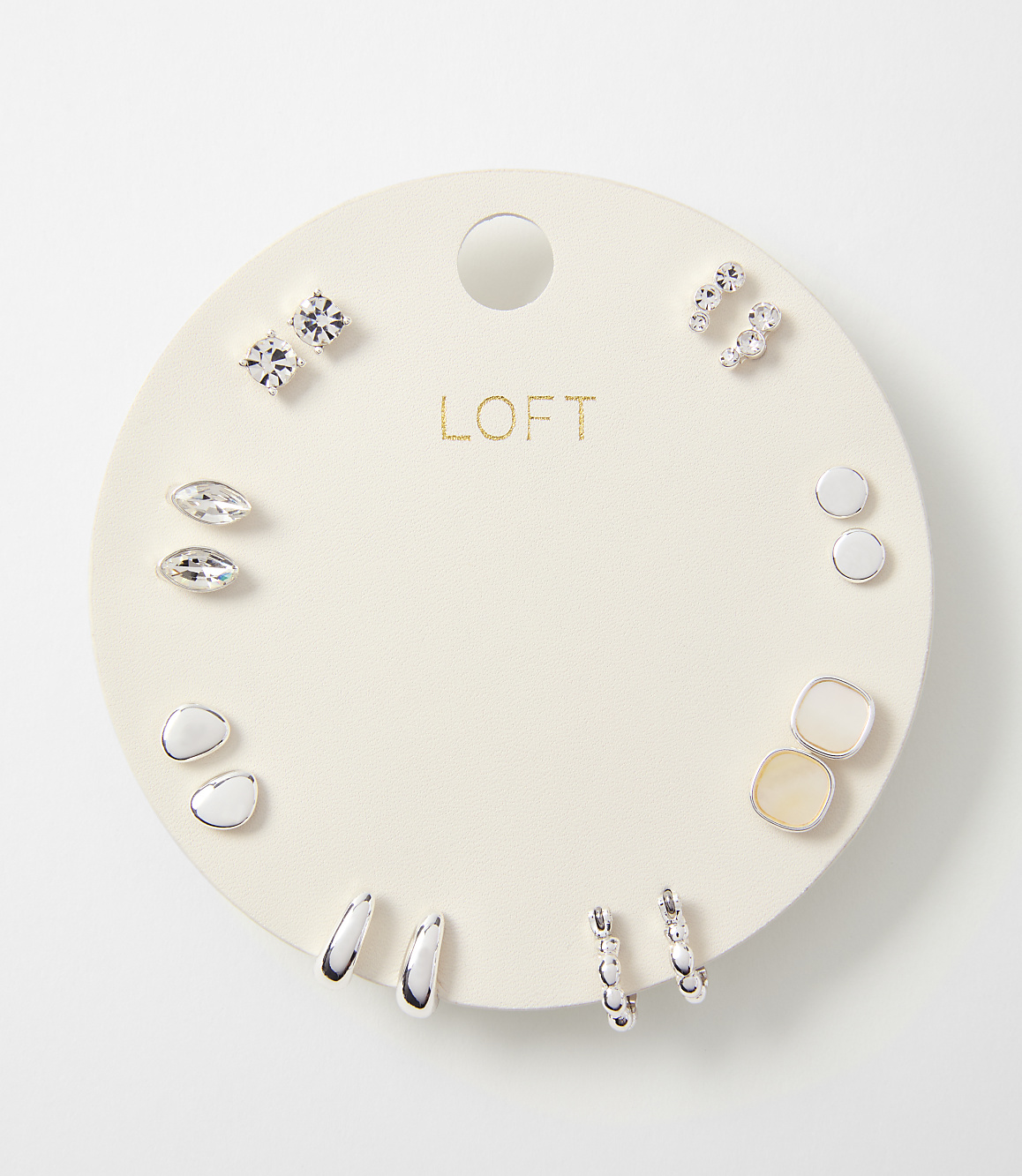 A circular white card displays a collection of assorted earrings, with the "LOFT" logo prominently featured in the center, against a plain white background.