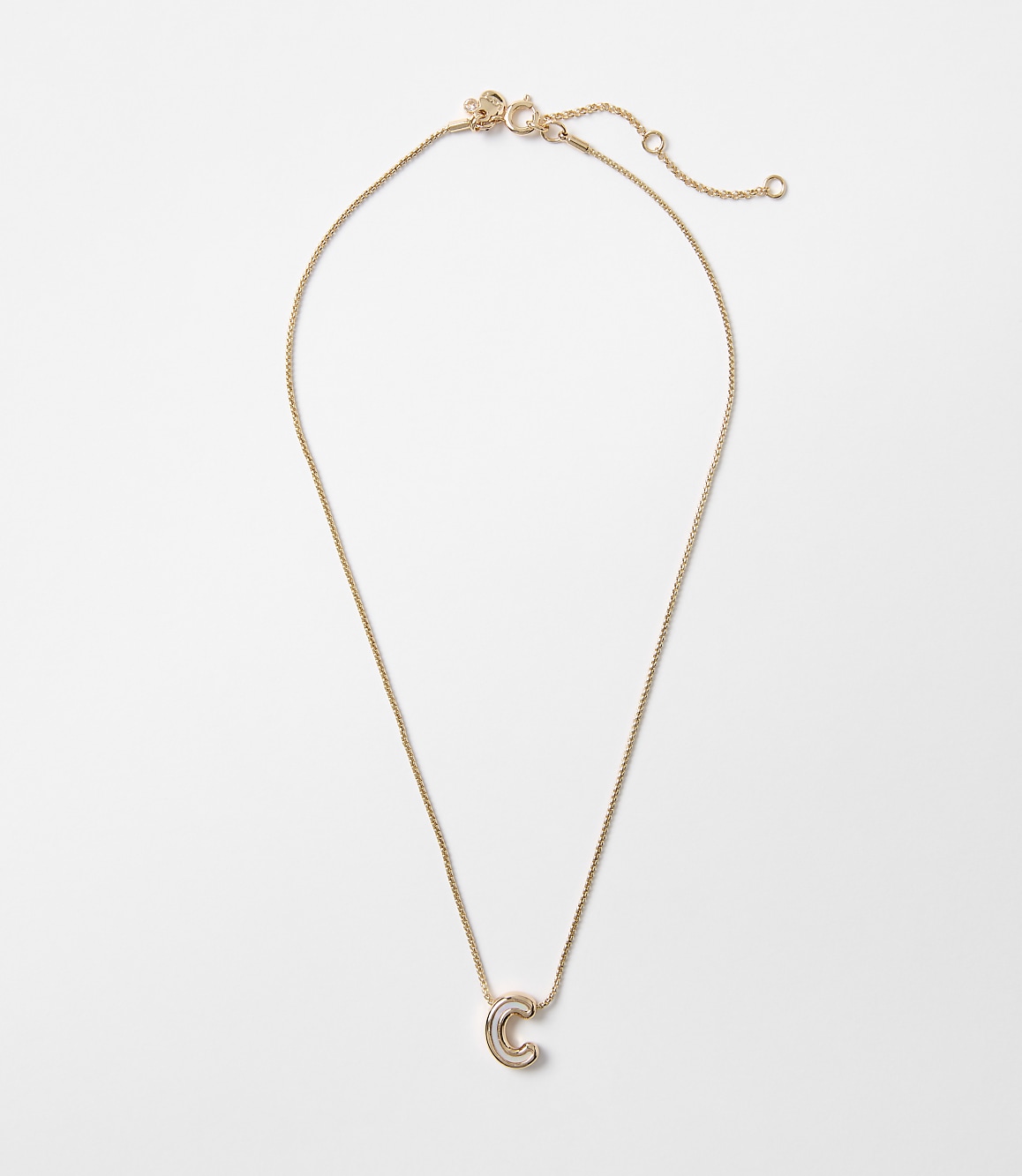 A delicate rose gold necklace with a lowercase "c" pendant hangs against a plain white background.