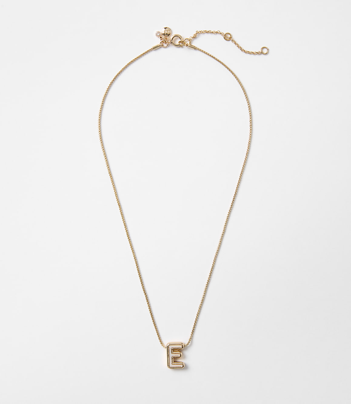 A delicate gold necklace with an "E" pendant rests on a plain white background.