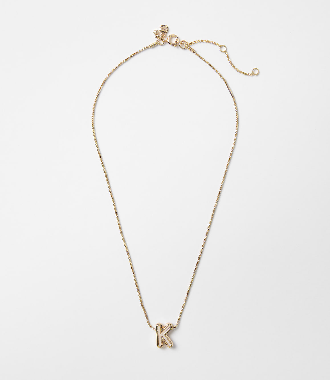 A delicate gold necklace with a letter "K" pendant rests on a plain white background.