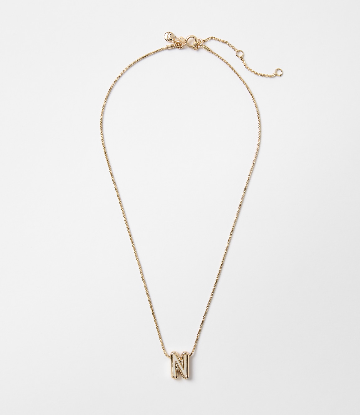 A delicate gold necklace with an "N" initial pendant hangs against a plain white background.