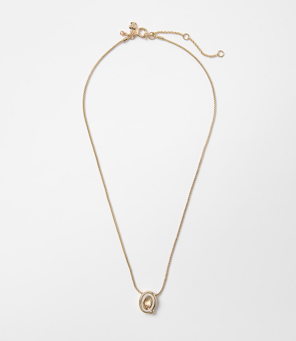 A delicate rose gold necklace with a small, oval pendant hangs against a plain white background.