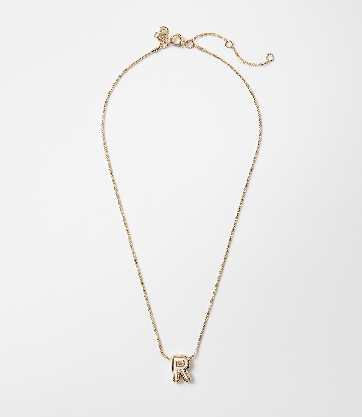 A delicate rose gold chain necklace with a single letter "R" pendant rests on a plain white background.