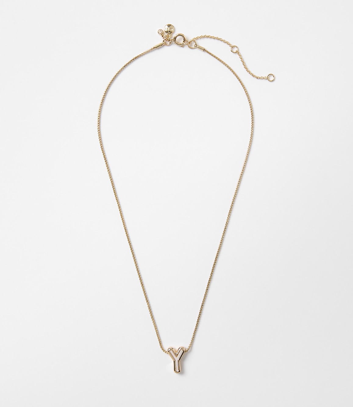 A delicate gold necklace with a lowercase "y" pendant hangs against a plain white background.