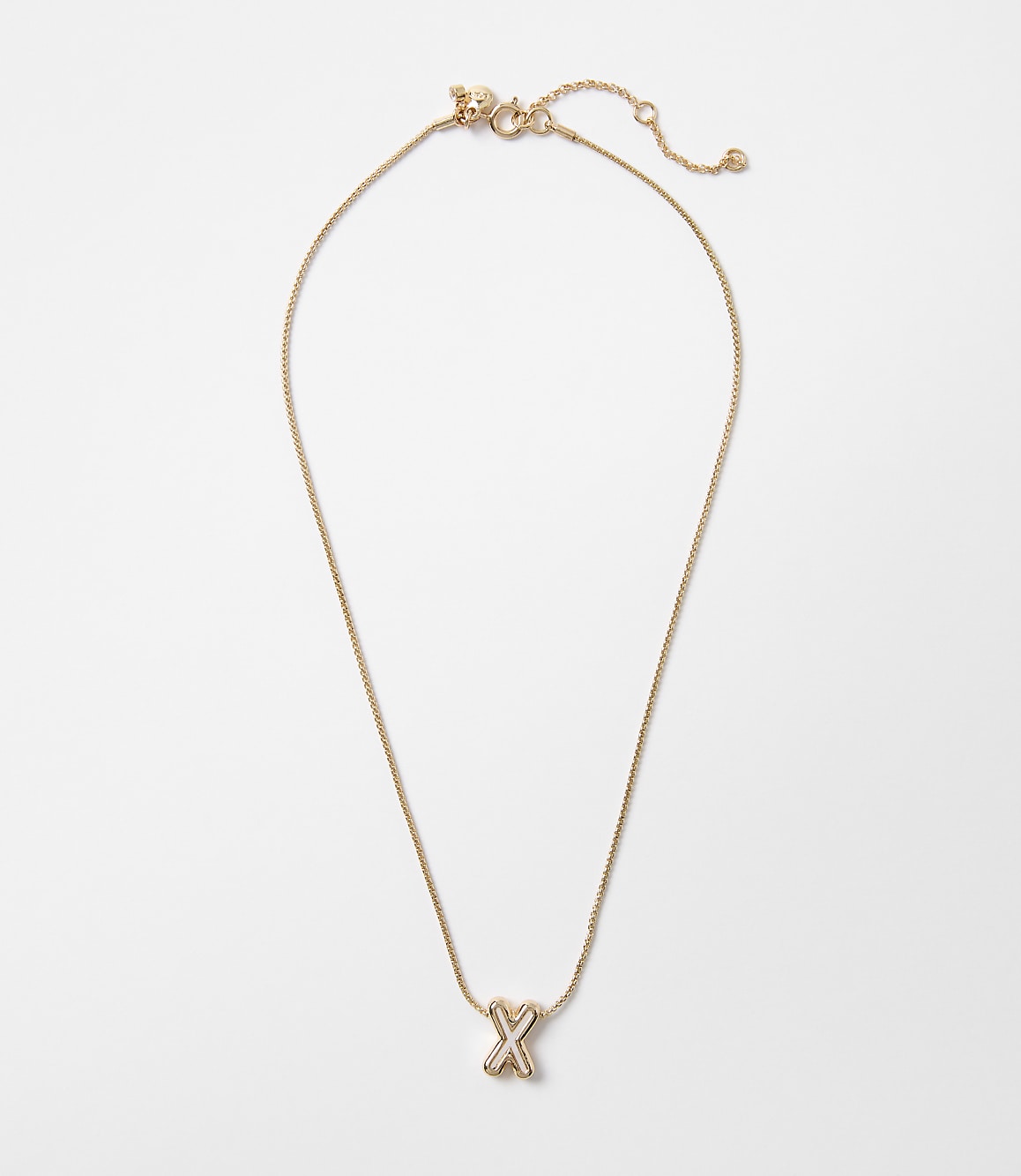 A delicate gold necklace with an "X" charm hangs against a plain white background.