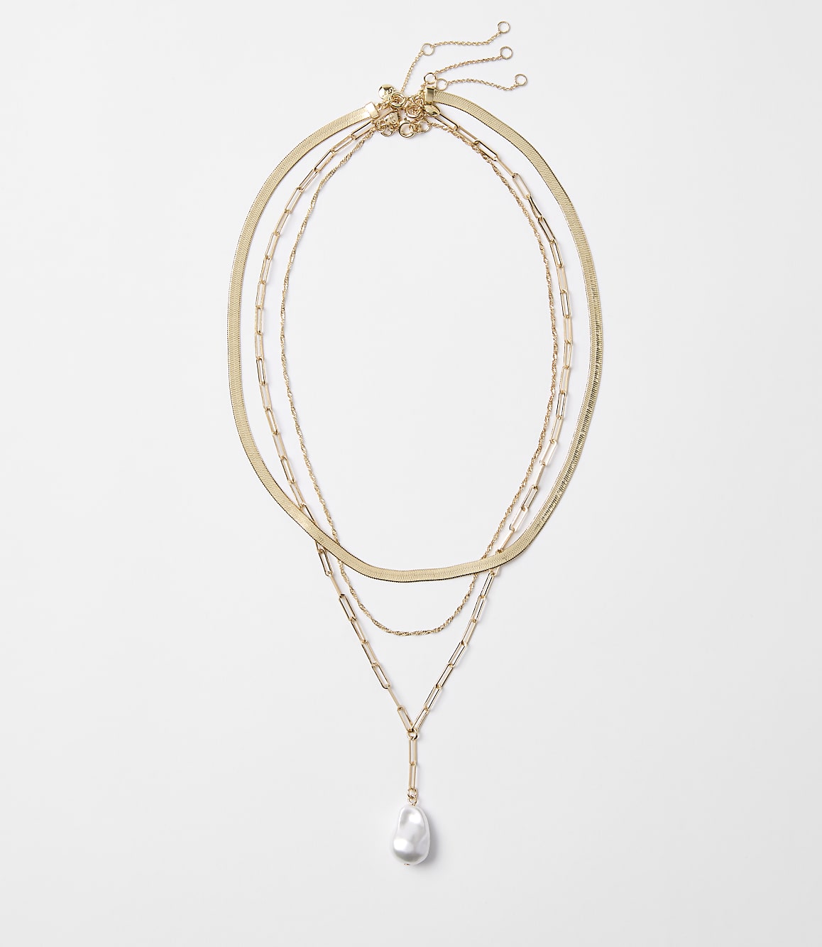 Three delicate gold necklaces, one with a single baroque pearl pendant, are arranged against a plain white background.