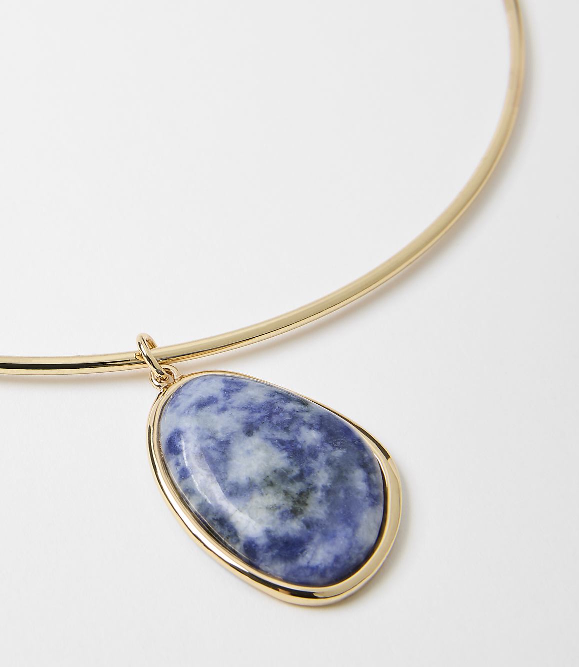 A gold choker necklace with a large, oval-shaped blue and white stone pendant hangs against a plain white background.