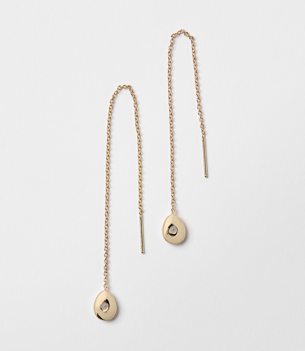 A pair of rose gold threader earrings with small, irregular pendants hang against a plain white background.