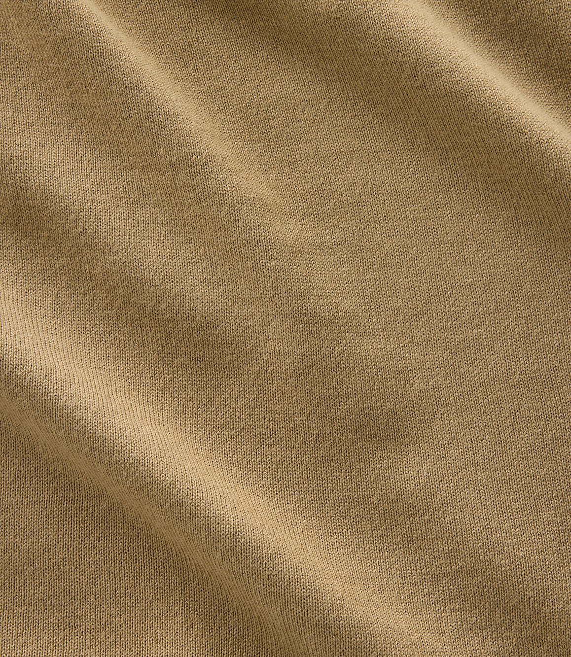 A close-up of tan fabric with soft folds and a textured weave fills the frame.