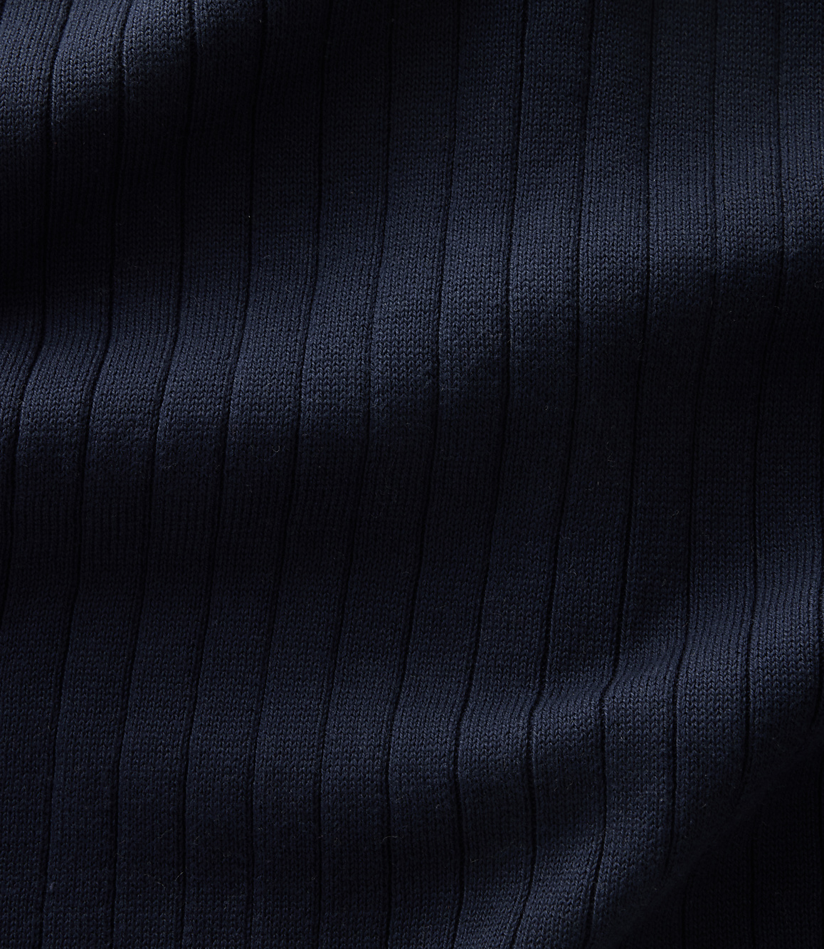 Dark navy ribbed fabric with vertical folds and shadows fills the frame.