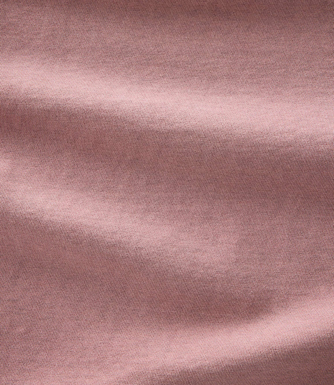 Soft, dusty rose fabric with gentle folds and shadows fills the frame.
