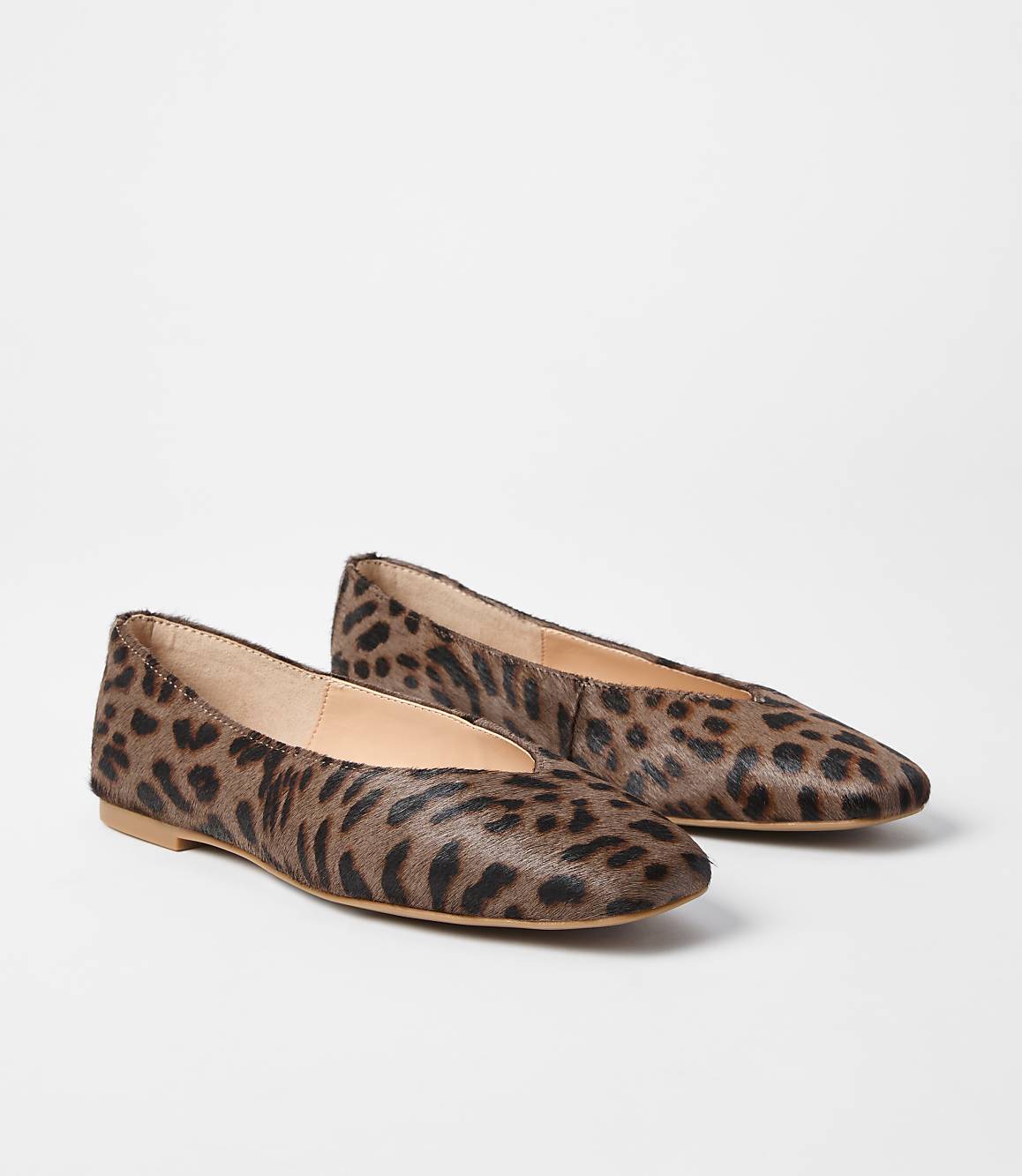 A pair of leopard-print ballet flats rests on a plain white background.