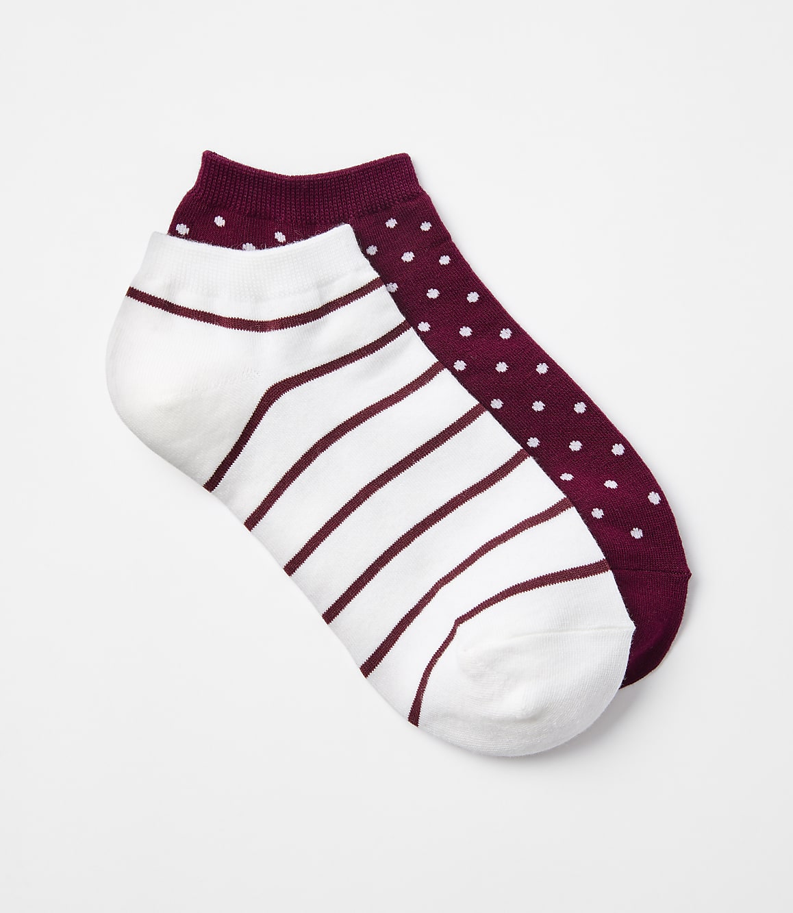 Two ankle socks, one white with maroon stripes and the other maroon with white polka dots, lie on a plain white background.