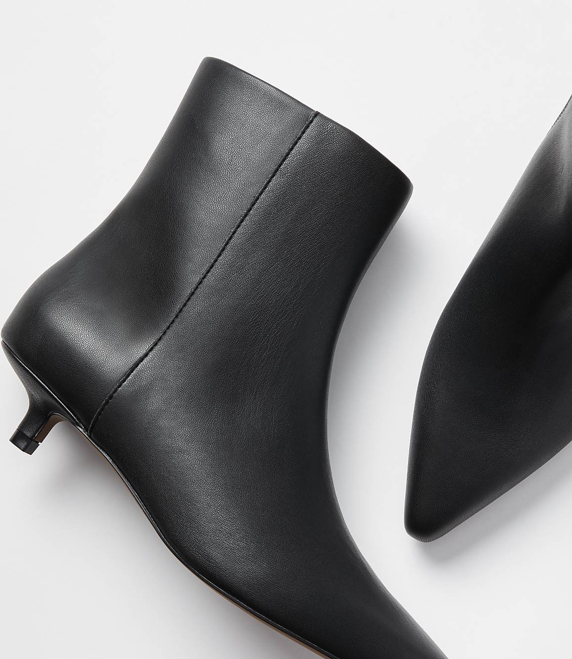 A pair of black leather kitten heel ankle boots are displayed against a plain white background.