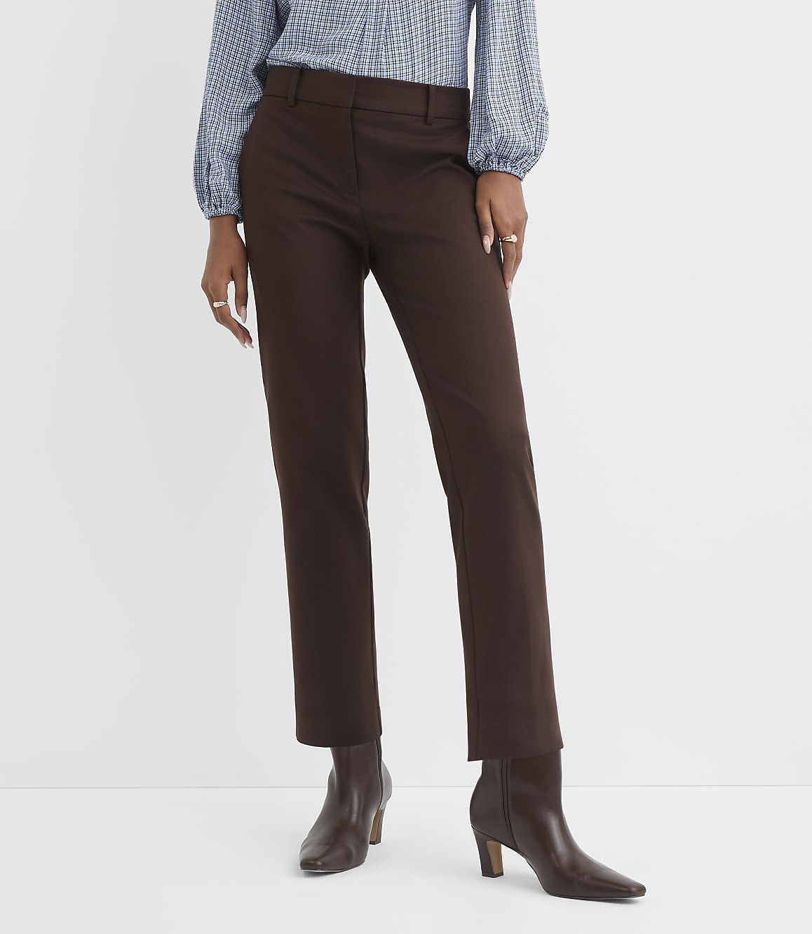 A person stands in brown pants and boots against a plain white background.