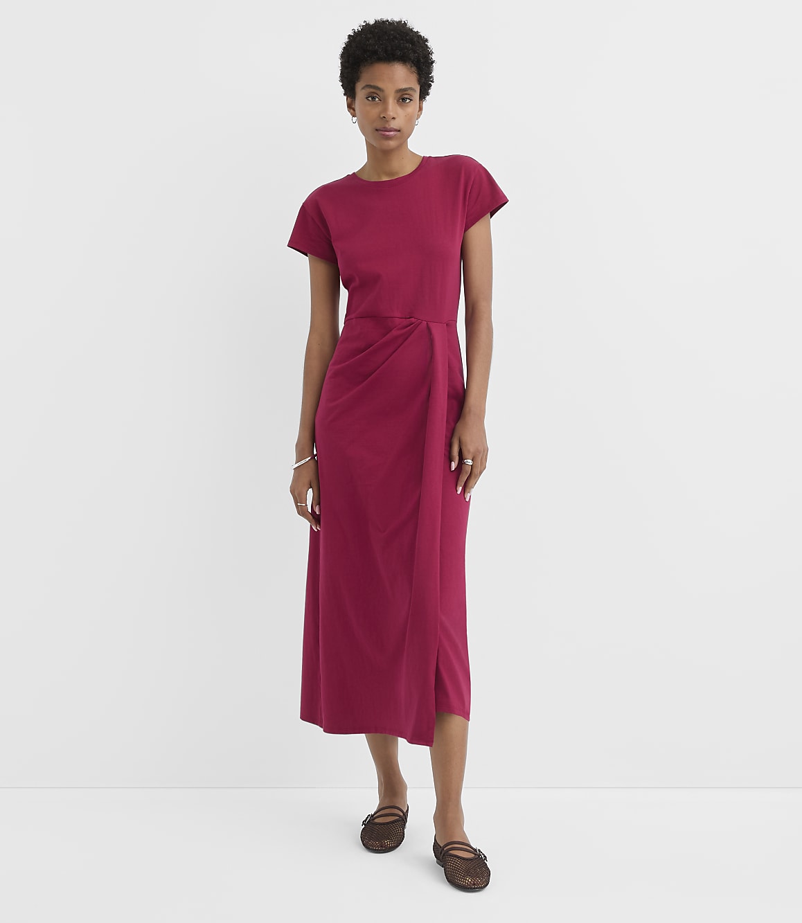A woman in a magenta dress stands against a plain white background.