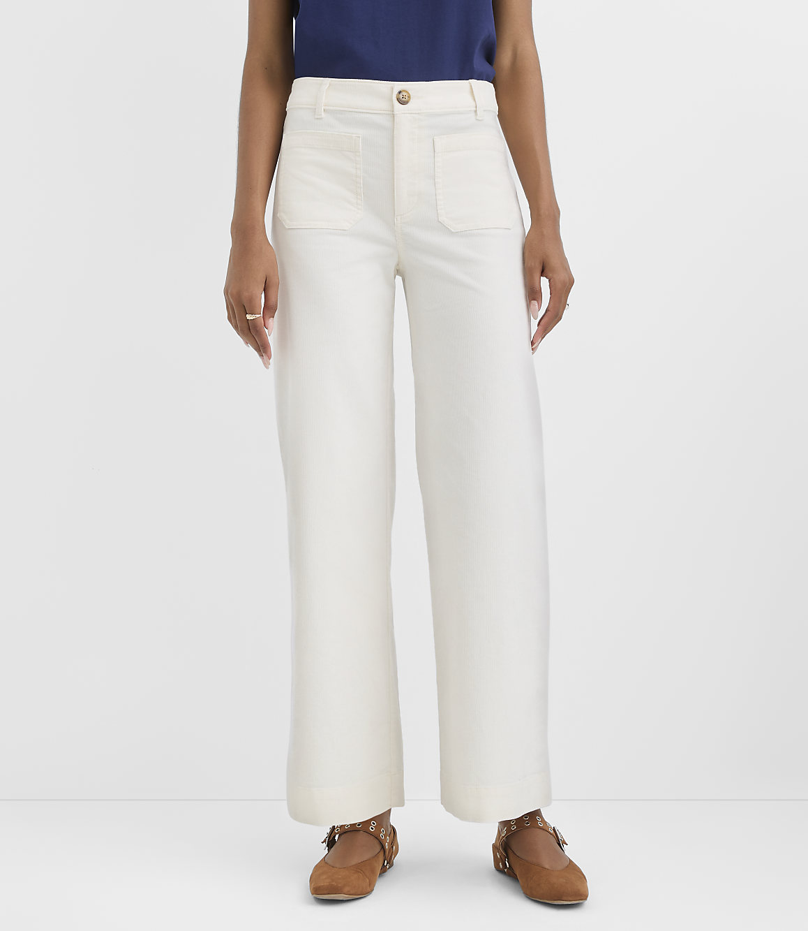 A person stands in white wide-leg pants and brown shoes against a plain white background.