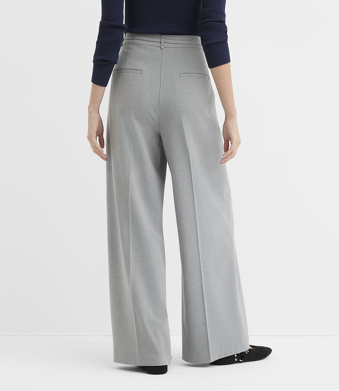 A person wearing gray wide-leg pants and black shoes stands against a plain white background.