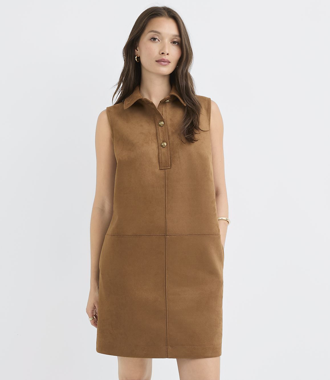 A woman in a brown suede shift dress stands against a plain white background.