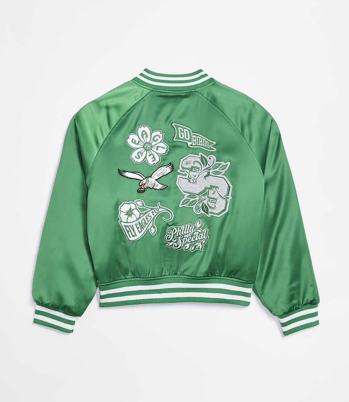 A green satin bomber jacket with various embroidered patches is displayed against a plain white background.