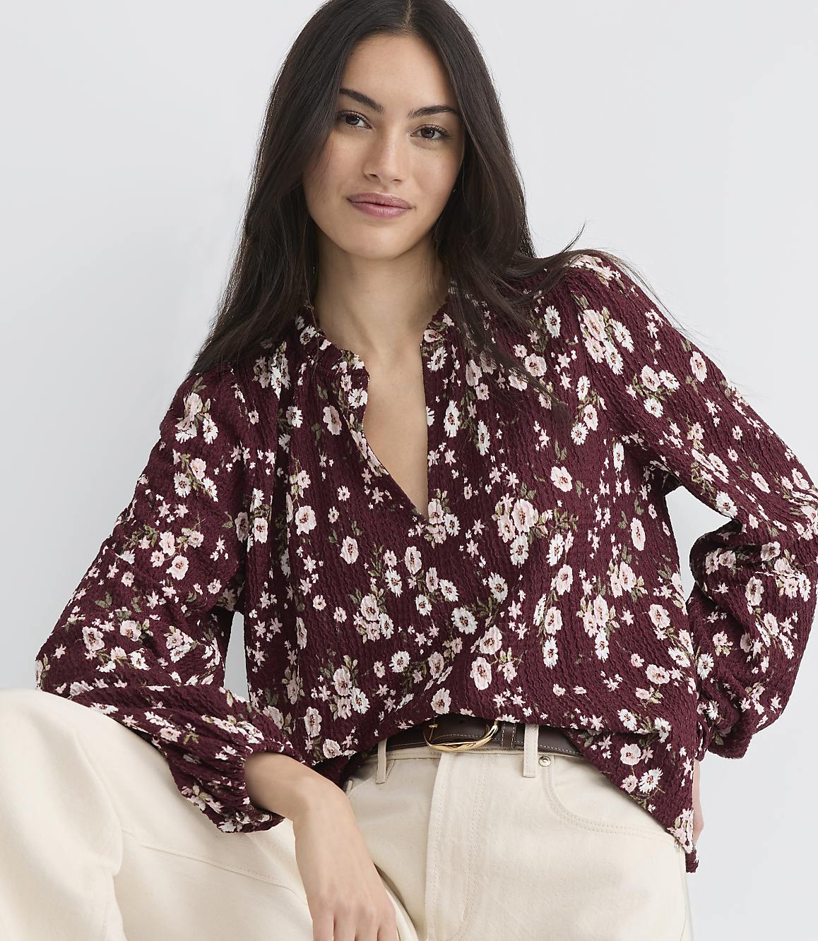 A woman in a floral blouse poses against a plain white background.