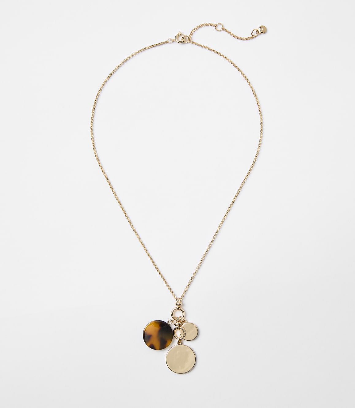 A delicate gold chain necklace with three circular pendants, one tortoiseshell and two gold, hangs against a plain white background.