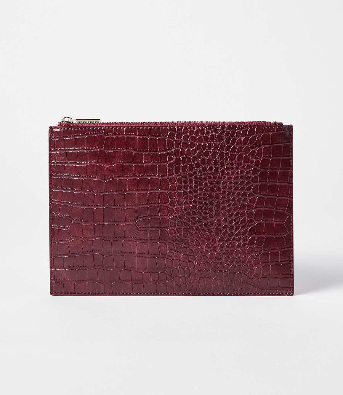 A deep red, crocodile-embossed clutch with a gold zipper rests on a plain white background.