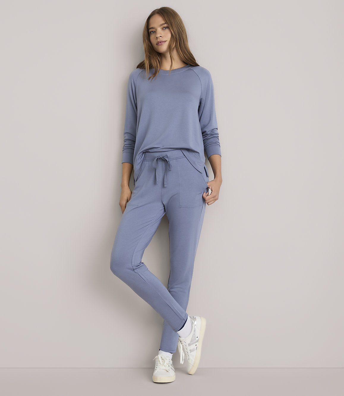 A woman in a blue loungewear set stands against a plain white background.