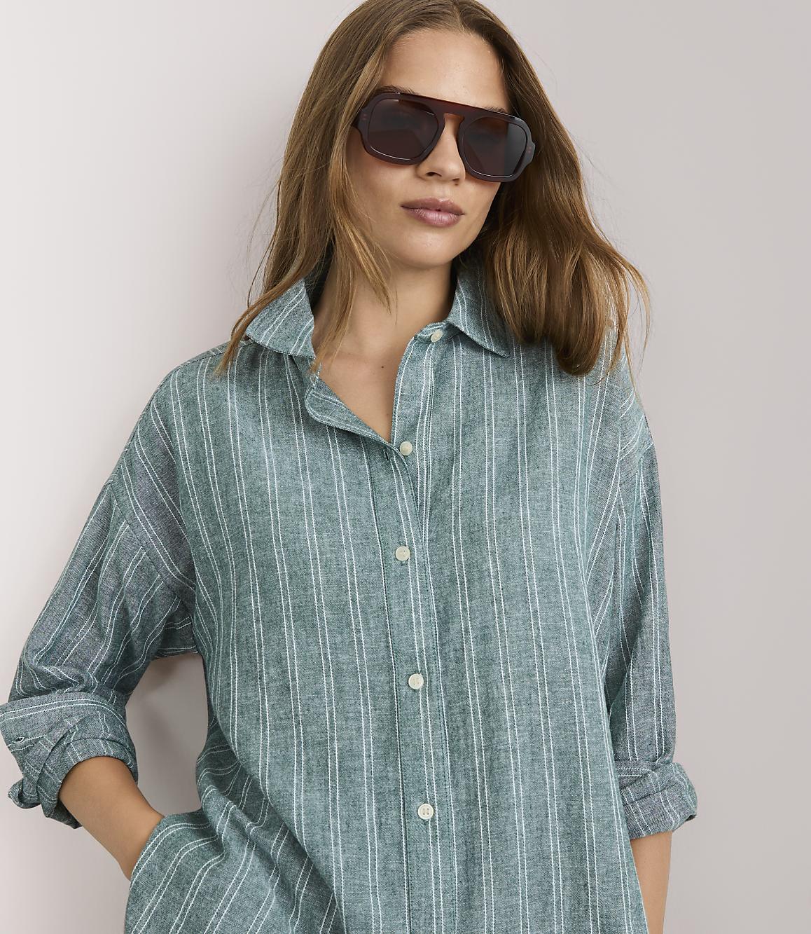 A woman in a striped pajama set stands against a plain white background.