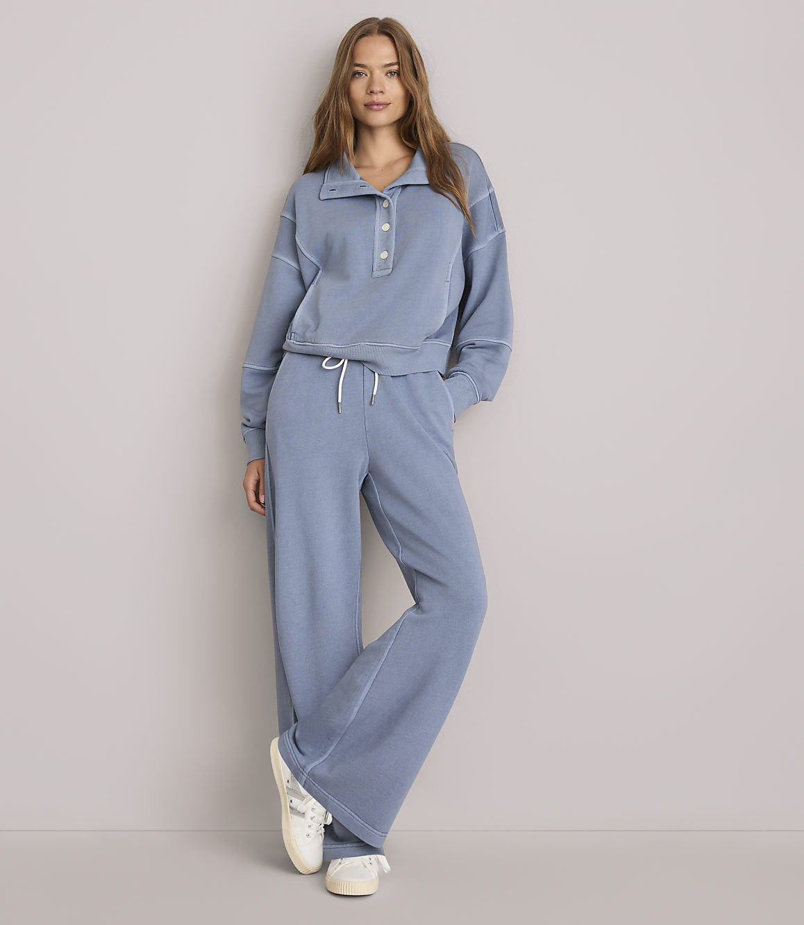 A woman in a blue loungewear set stands against a plain gray background.