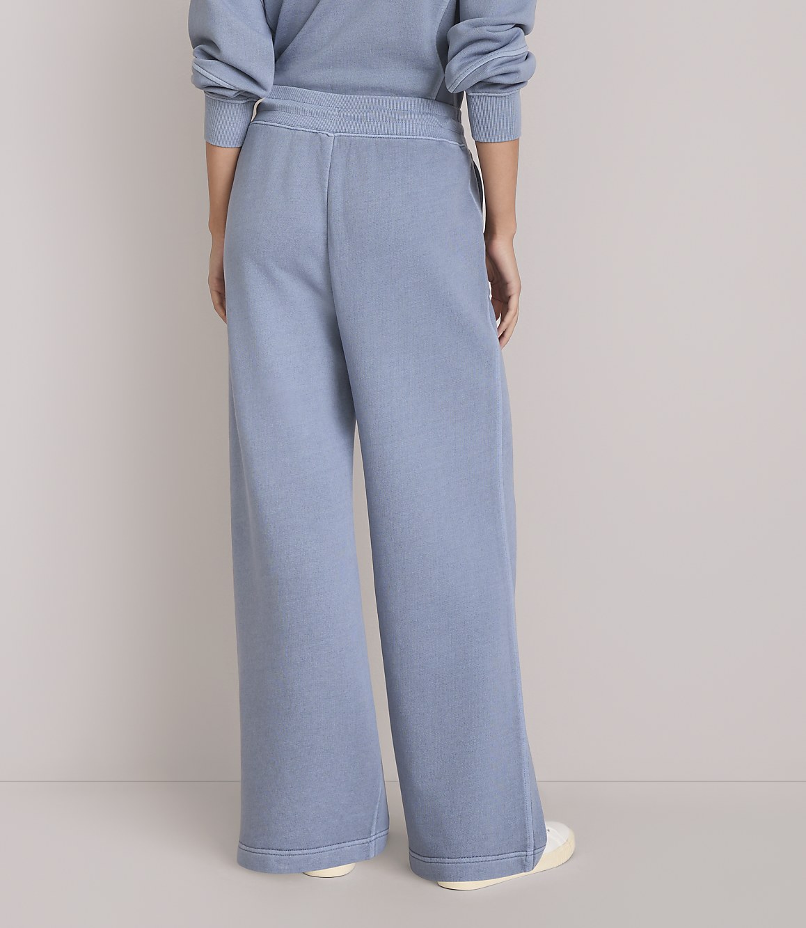 A person wearing light blue wide-leg sweatpants stands against a plain white background.