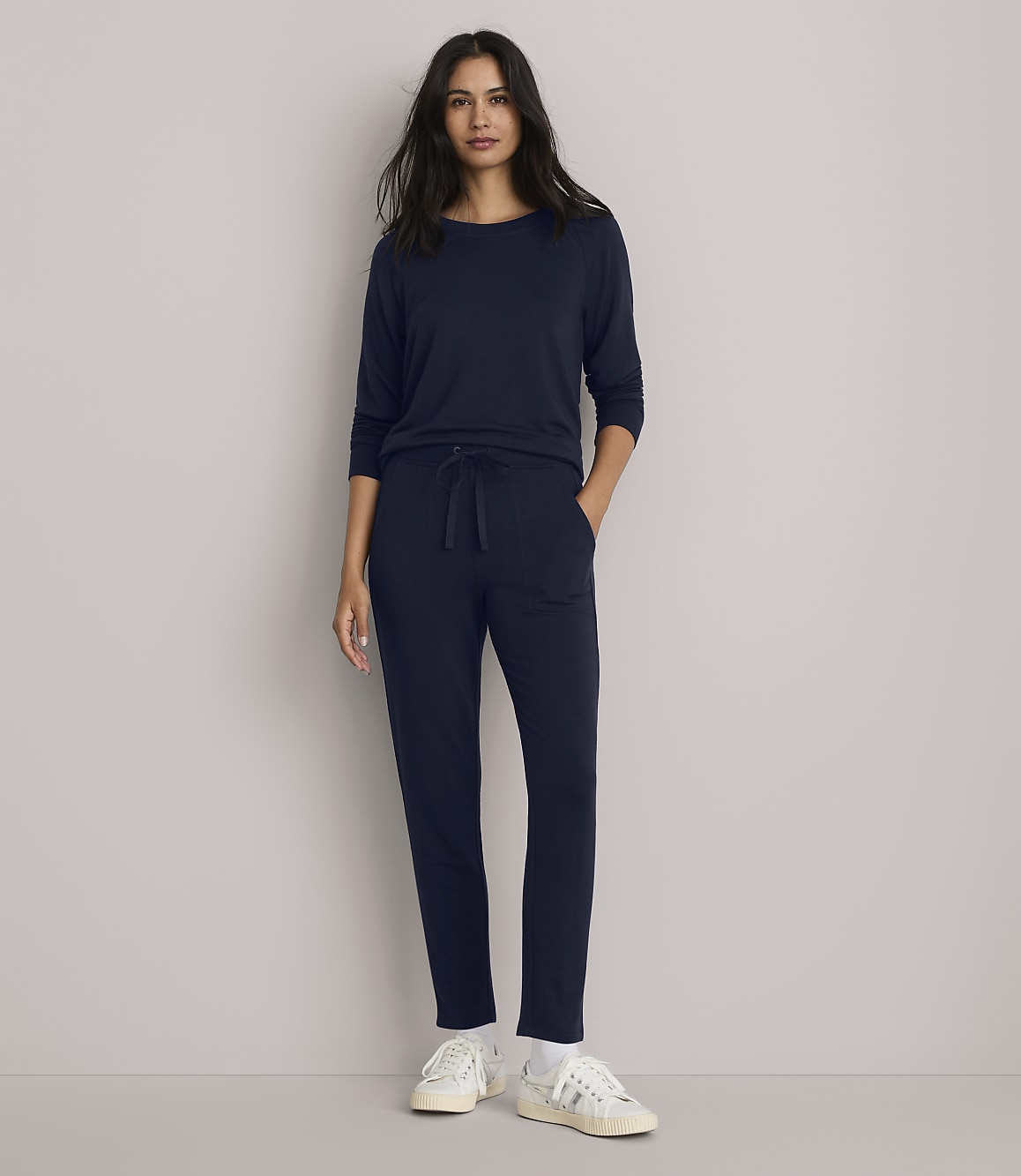 A woman in a navy blue loungewear set stands against a plain gray background.